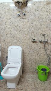 a bathroom with a toilet and a green bucket at Tea corner Guest house in Darjeeling