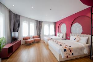 a bedroom with two beds and a pink wall at Palette Collect's Boutique Hotel Ha Long in Ha Long