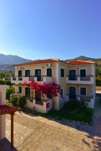 a large white house with red flowers on the balcony at So Nice Hotel in Marathokampos