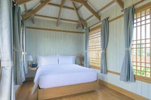 a bedroom with a white bed and two windows at K-Town Resort Phan Thiet in Phan Thiet