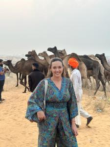 una mujer parada frente a un grupo de camellos en Hotel Zoola Palace en Pushkar