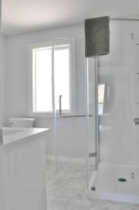 a white bathroom with a shower and a sink at 4 BR Home - Close by the River in Kamloops