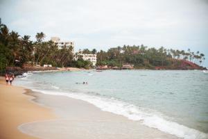 una playa con gente en el agua y palmeras en Tropical Inn, en Mirissa