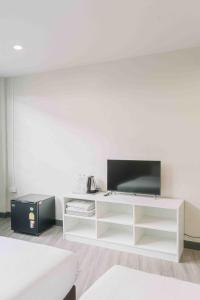 a living room with a tv on a white shelf at Ma Non Nont Hotel & Apartment in Nonthaburi
