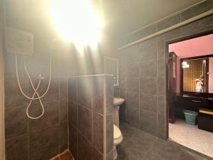 a bathroom with a toilet and a light on the wall at Lanta Garden Home in Ko Lanta