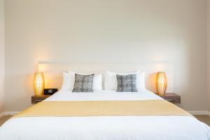 a bedroom with a large white bed with two lamps at The Marina Hotel - Mindarie in Mindarie