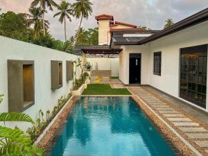a swimming pool in front of a house at Villa River Breeze in Weligama