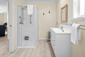 a white bathroom with a shower and a sink at Sea Breeze Cottage - Convenient! in Bicheno