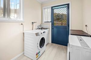 pralnia z pralką i niebieskimi drzwiami w obiekcie Sea Breeze Cottage - Convenient! w mieście Bicheno