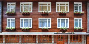 a wooden building with white windows and potted plants at Udaan Woodberry Hotel & Spa in Gangtok