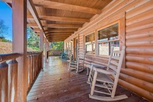 a porch of a cabin with rocking chairs on it at Bearfoot Pines - True Log Cabin - Wi-Fi, Hot Tub, Fishing, Deck with views! - Mins to PF in Sevierville