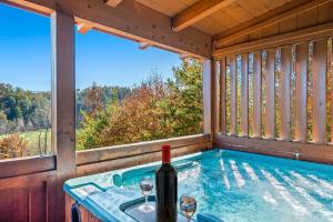 ein Whirlpool mit einer Flasche Wein und Gläsern in der Unterkunft Bearfoot Pines - True Log Cabin - Wi-Fi, Hot Tub, Fishing, Deck with views! - Mins to PF in Sevierville