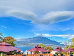a mountain in the distance with red umbrellas and water at Fuji Yamanakako Resort Hotel in Yamanakako