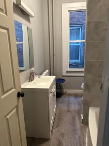 baño blanco con lavabo y ventana en Wonderful West Philly Apt, en Filadelfia