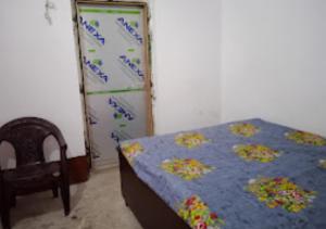 1 dormitorio con 1 cama, 1 silla y nevera en Hotel Kameshwar Rajgir, en Rajgir