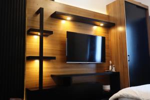 a bedroom with a tv on a wooden wall at Kozen at Azure North Pampanga in San Fernando