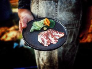 a person holding a plate with meat and vegetables at Murdoch + Luxury + Experience in Lebrina