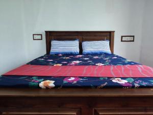 a bed with a floral bedspread and two pillows at The Duke in Weligama