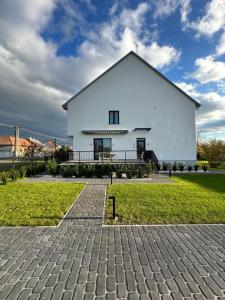 a large white house with a brick driveway at NP2 Apartman in Bük