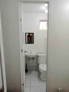 a white bathroom with a toilet and a sink at Noana Crib in Davao City