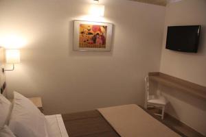 1 dormitorio con 1 cama y TV en la pared en La Papagna Dimora Storica, en Palagianello