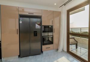a stainless steel refrigerator in a kitchen with a balcony at Aqua Penthouse Beach Apartment in Mombasa