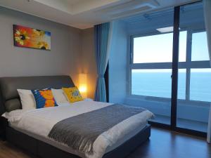 a bedroom with a bed and a large window at 이스턴뷰 프리미엄 레지던스 100프로오션뷰 in Ulsan