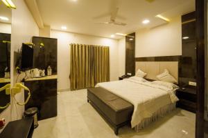 1 dormitorio con 1 cama y TV en Hotel Celebration, en Jamnagar