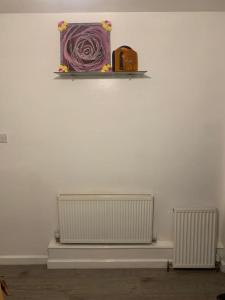 two radiators on a wall with a shelf above them at Arden Street in Gillingham