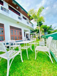 a group of white chairs and tables in front of a building at Srilak View Holiday Inn in Haputale