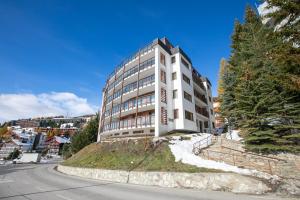 un edificio blanco en la cima de una colina al lado de una calle en Terrazza Dei Principi Few Steps From Ski - Happy Rentals en Sestriere