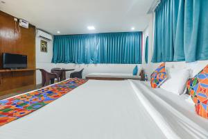1 dormitorio con 1 cama blanca grande y cortinas azules en FabExpress Stargaze Beach, en Anjuna
