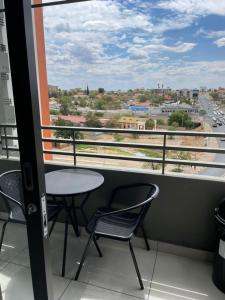 balcón con mesa, sillas y vistas a la ciudad en Dmn City Apartment at Junction en Windhoek