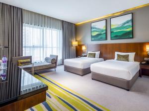 a hotel room with two beds and a couch at Flora Al Barsha Hotel At The Mall in Dubai