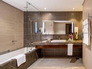 a bathroom with a tub and a sink and a shower at Flora Al Barsha Hotel At The Mall in Dubai