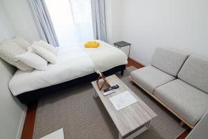 een kleine slaapkamer met een bed en een bank bij SQ) SHIBUYA HOUSE in Tokyo