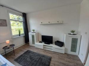 a white living room with a television and a window at Ferienwohnung Landliebe in Süderschweiburg