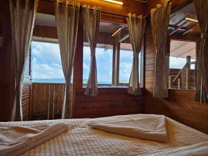 Bett in einem Zimmer mit Fenstern und Bettblende in der Unterkunft Himalayan Havenwood in Mukteswar