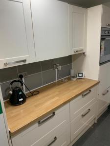 una cucina con armadi bianchi e ripiano in legno di Gordon Road a Gillingham