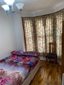 ein Schlafzimmer mit einem Bett, einem Stuhl und Vorhängen in der Unterkunft Gordon Road in Gillingham