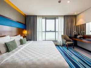 a hotel room with a large bed and a desk at Flora Al Barsha Hotel At The Mall in Dubai