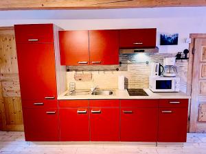 a red kitchen with a sink and a microwave at Sweet Mountain Home in Bad Bleiberg