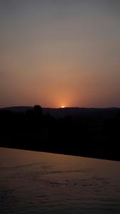 a sunset over a field with a body of water at Anopura Jaipur in Jaipur
