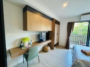 Schlafzimmer mit einem Schreibtisch und einem Bett sowie einem Balkon in der Unterkunft HuaHin La Casita condo Quiet, cozy room Netflix#1 in Hua Hin