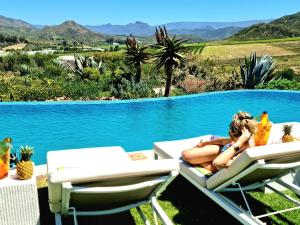 a woman laying on a chair next to a swimming pool at PJURE Wellness Retreat & Spa in Montagu