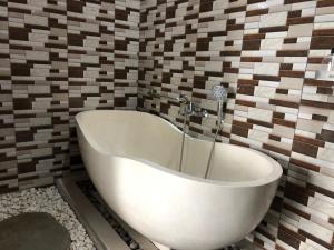 a bath tub in a bathroom with a tile wall at Sedana Yoga Resort in Jembrana