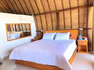 a bedroom with a white bed and a mirror at Sedana Yoga Resort in Jembrana