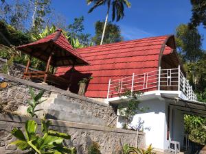 a house with a red roof and a stone wall at Sedana Yoga Resort in Jembrana