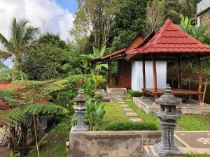 a garden with a small building with a red roof at Sedana Yoga Resort in Jembrana