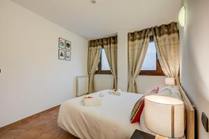una camera da letto con un letto bianco, una sedia e finestre di L' Aquila Campo Smith On The Ski Slopes - Happy Rentals a Bardonecchia